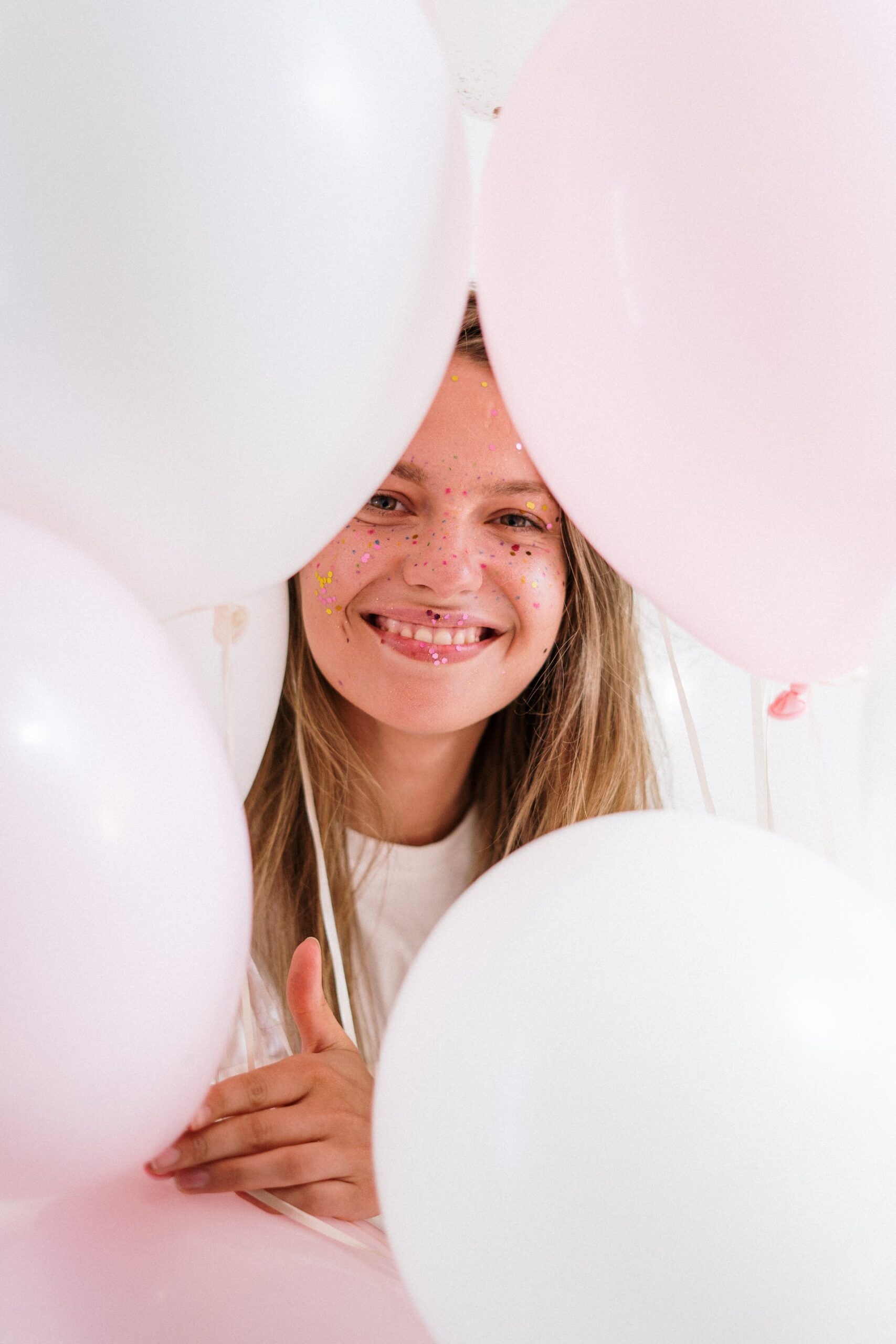 A young girl smiling while holding balloons | Source: Pexels