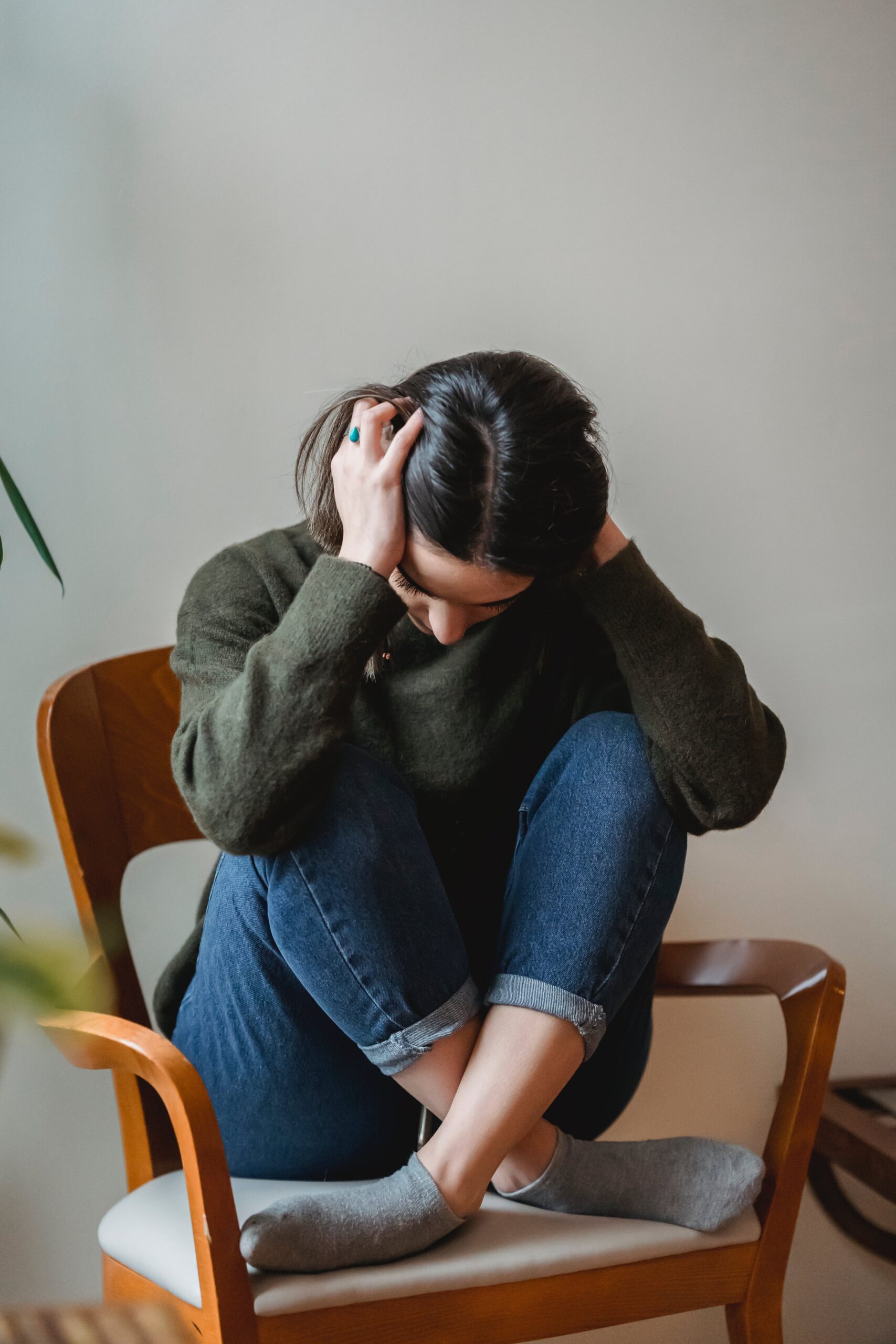 A frustrated woman sitting on a chair with her hands over her ears and head | Source: Pexels