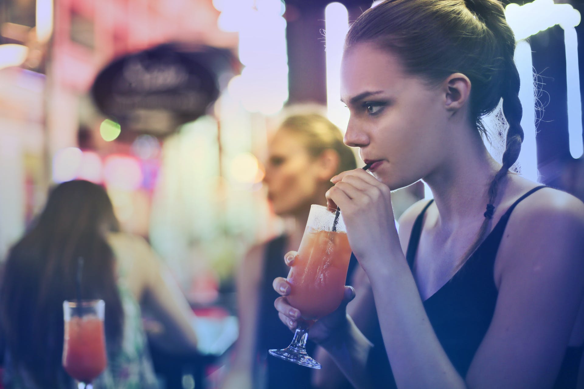Woman sipping on a cocktail | Source: Pexels