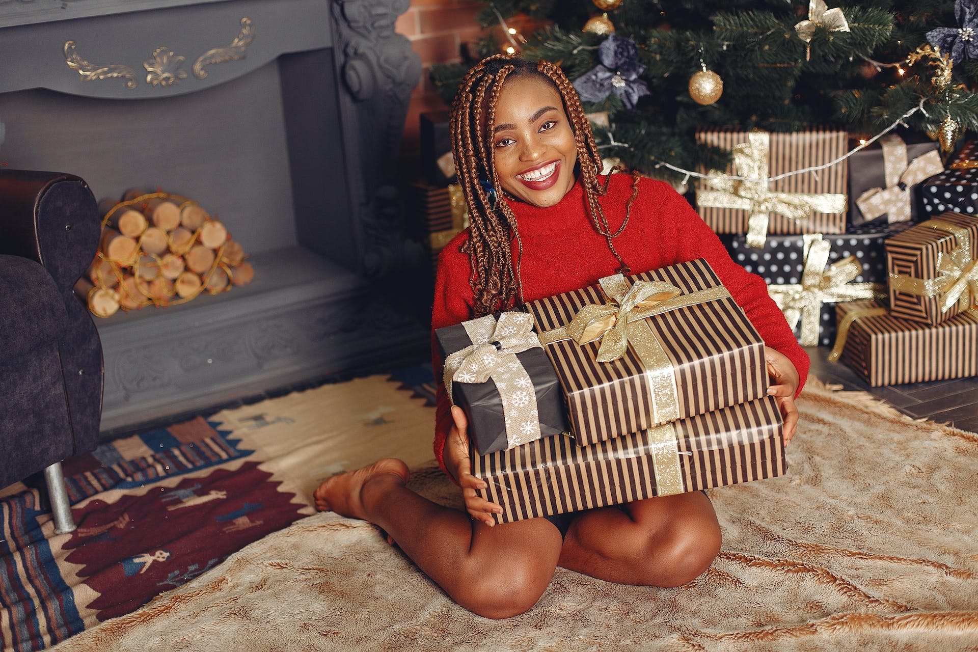 A smiling black woman holding gift boxes | Source: Pexels