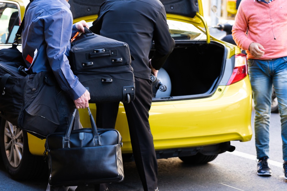 Passengers loading their luggages in the trunk of taxi. | Source: Shutterstock